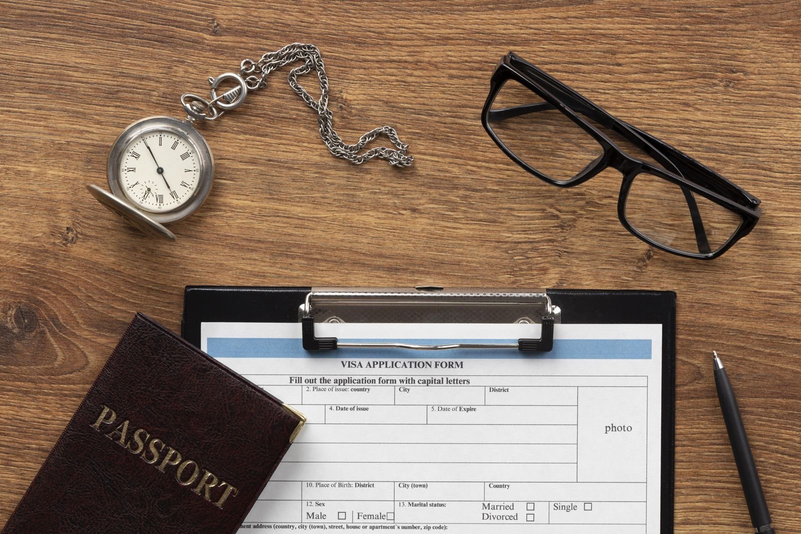 Visa application form, passport and pen on a desk