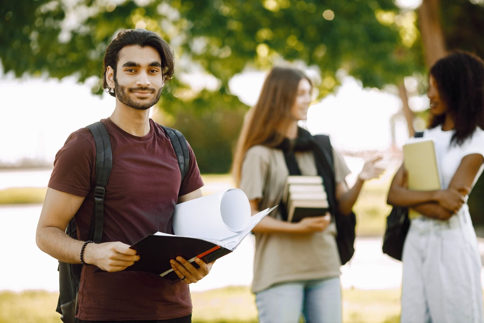 An Indian student with books standing with international classmates on a university campus